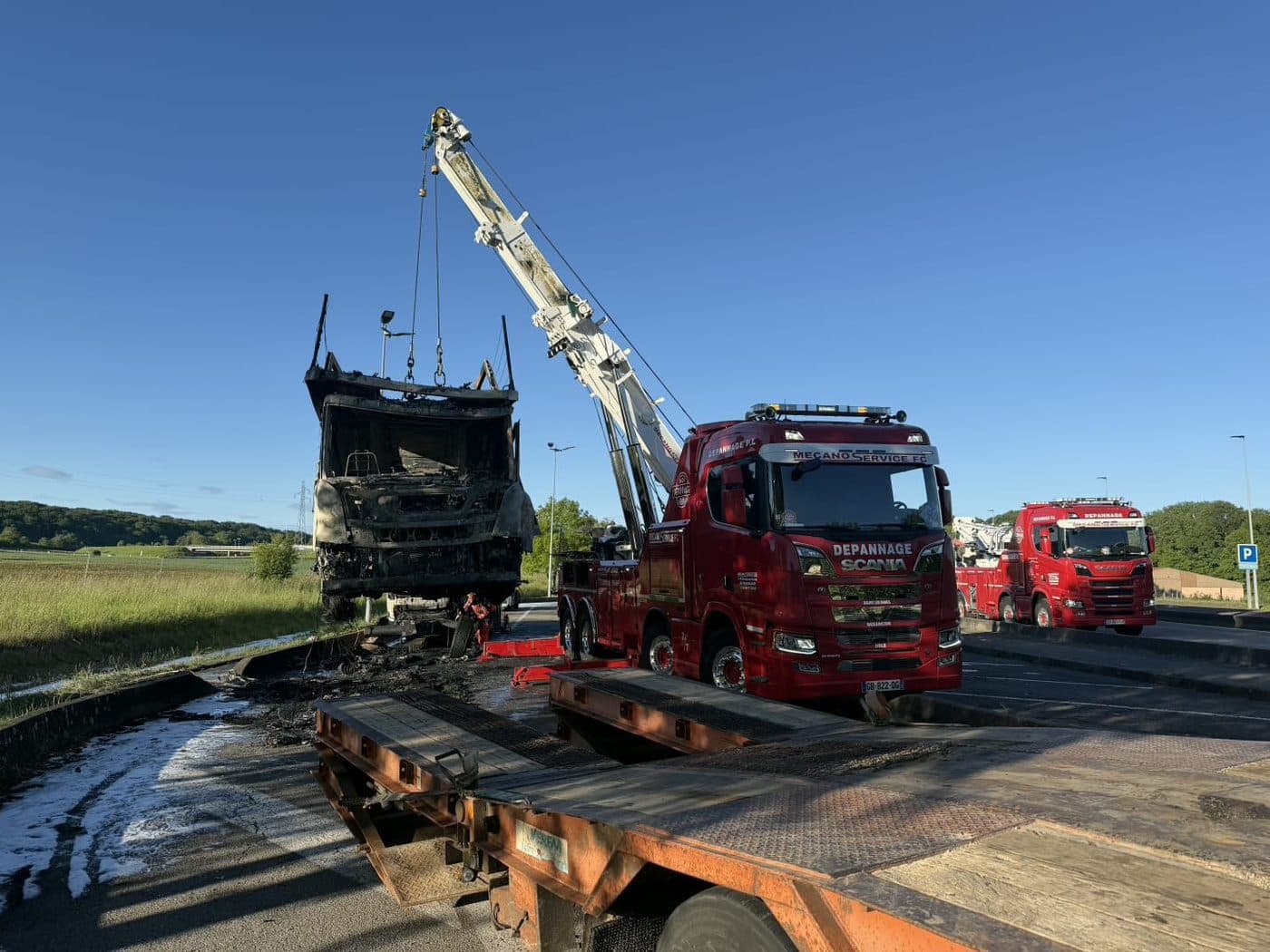 Grue d'un dépanneur partenaire relevant une benne accidentée